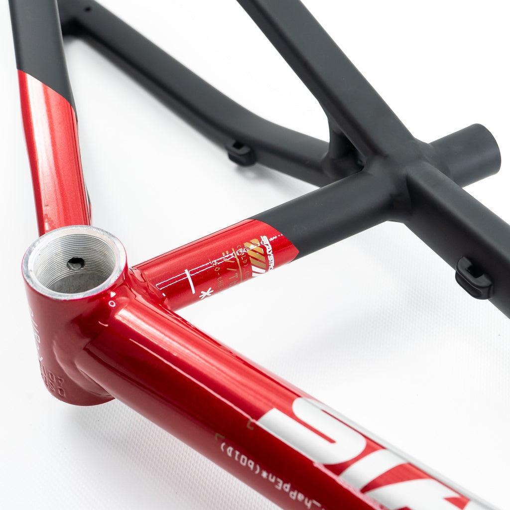 Close-up of the Staystrong V5 Disc Mini Frame showing red and black painted tubes with detailed graphics, an exposed threaded bottom bracket shell, and a disc brake mount.