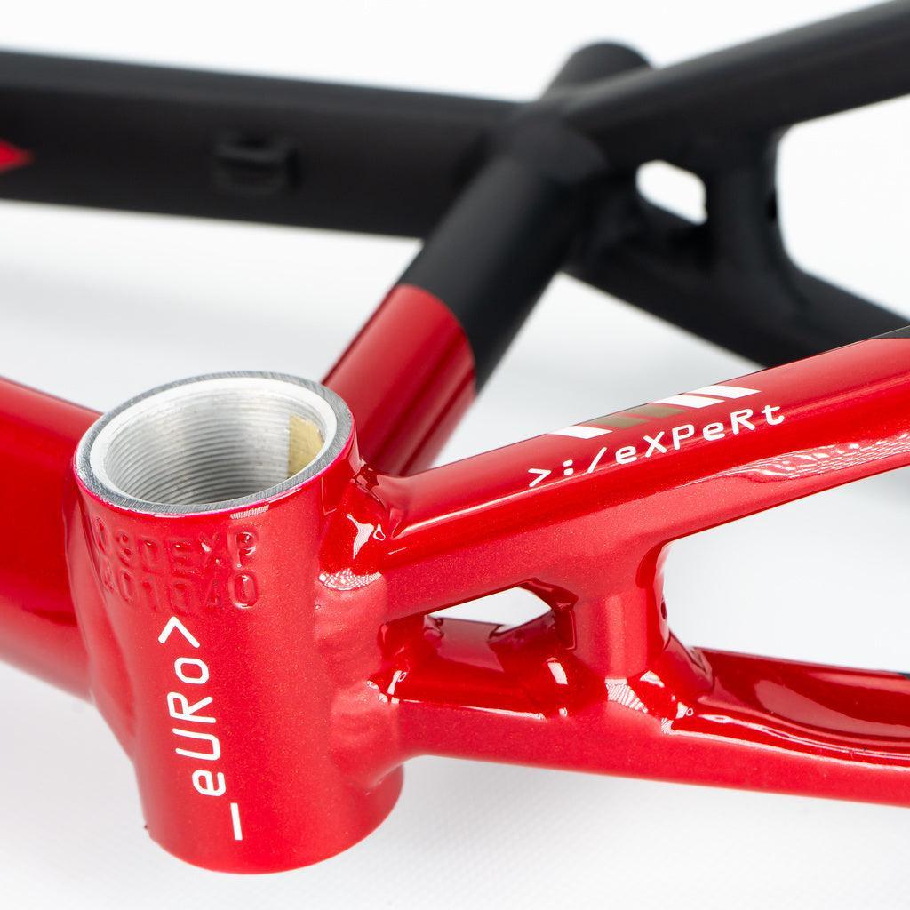 Close-up of a red Staystrong V5 Disc Mini Frame, showing "euro" and "zi/eXPeRt" text, the bottom bracket shell, part of the black rear triangle, and disc brake mounts. Inspired by the iconic Stay Strong V5 design.