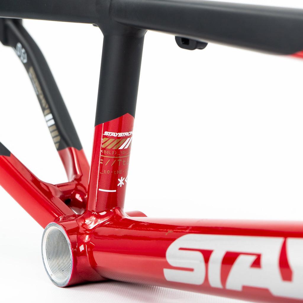 Close-up of a Staystrong V5 Disc Mini Frame in red aluminium with white graphics, highlighting the bottom bracket and part of the seat tube, shown with a disc brake.