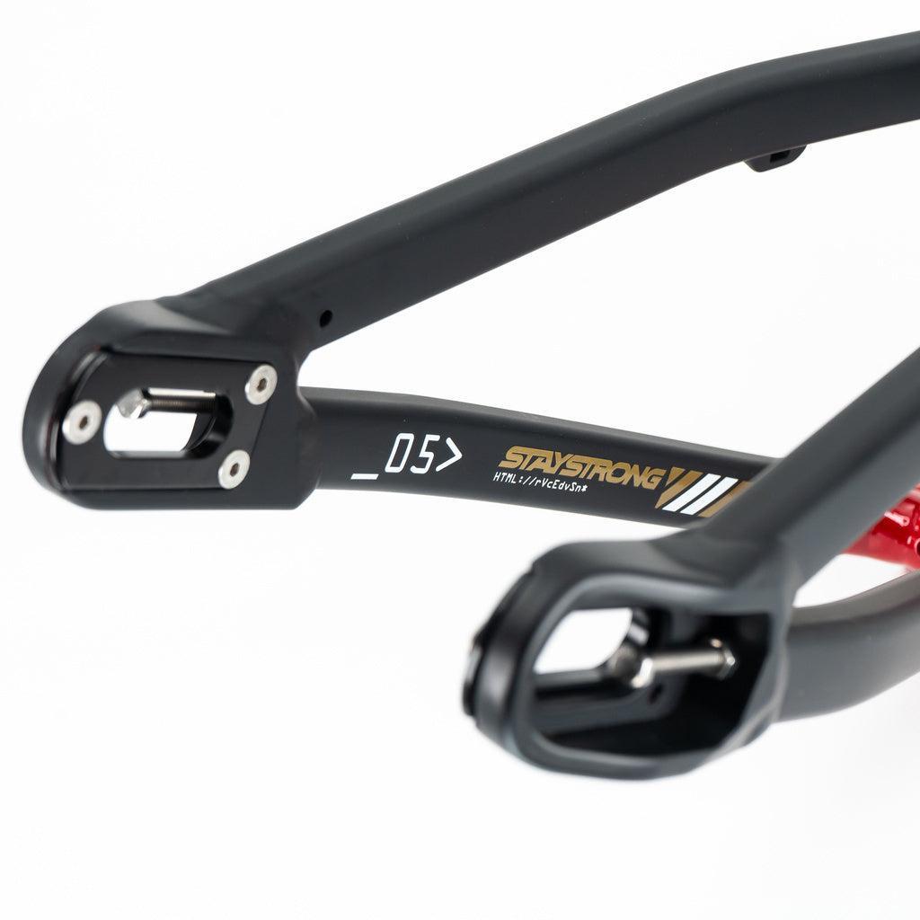 Close-up of the Staystrong V5 Disc Mini Frame's black aluminum rear dropout, featuring disc brake mounts, "STAYSTRONG" branding, and white graphics on a clean white background.