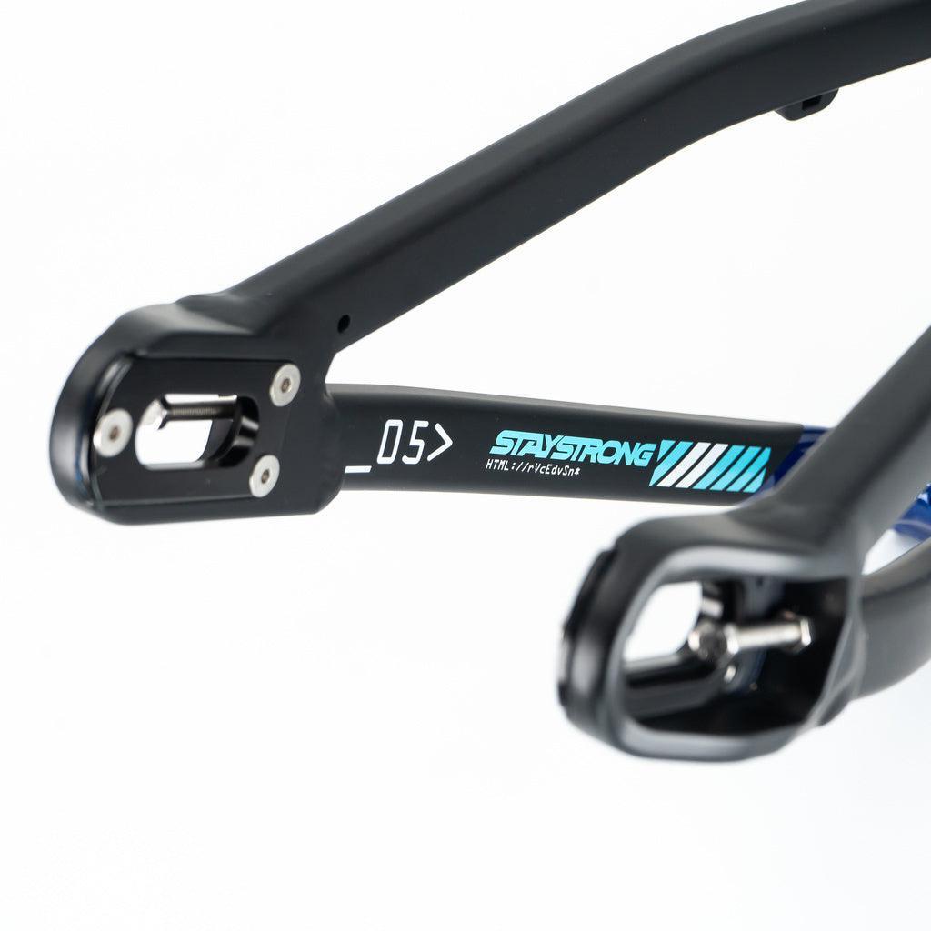 Close-up of the Staystrong V5 Disc Junior Frame’s black aluminium rear dropout, featuring “STAYSTRONG” branding, blue accents, and a disc brake mount on a white background.