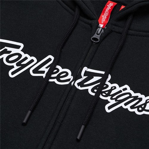 Close-up of the TLD 26.1 Zip Up Hoodie in black with "Troy Lee Designs" in white script across the chest, a red TLD tag on the zipper, and a cozy hood—ideal for frosty mornings.