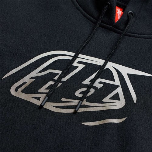 Close-up of the TLD 26.1 Pullover Hoodie Badge Black featuring a stylized silver graphic, black drawstrings, and a small red neck tag—ideal for warmer layers and inspired by Troy.