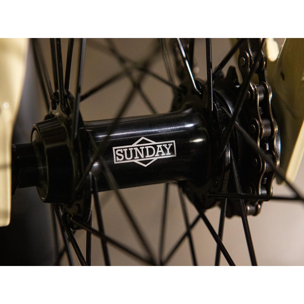 Close-up of a bicycle wheel hub with black spokes and "SUNDAY" printed in white on the hub, highlighting the quality and sleek design featured on the Sunday High C 29 Inch Bike.