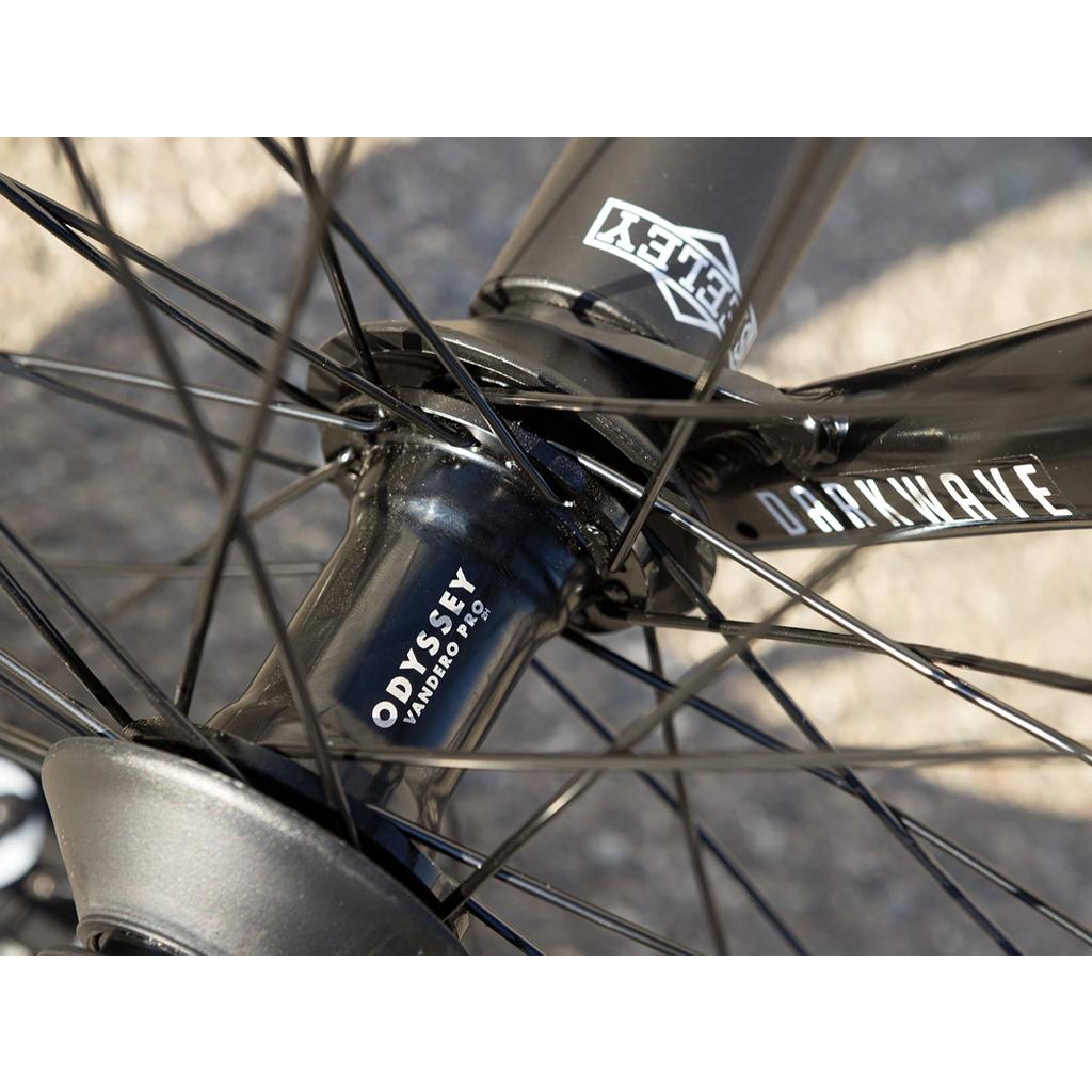 Close-up of a black "ODYSSEY VANDERO PRO" hub with spokes, featuring part of the Sunday Dark Wave Authentic 20 Inch Bike frame and visible "DARKWAVE" and "RILEY" decals.
