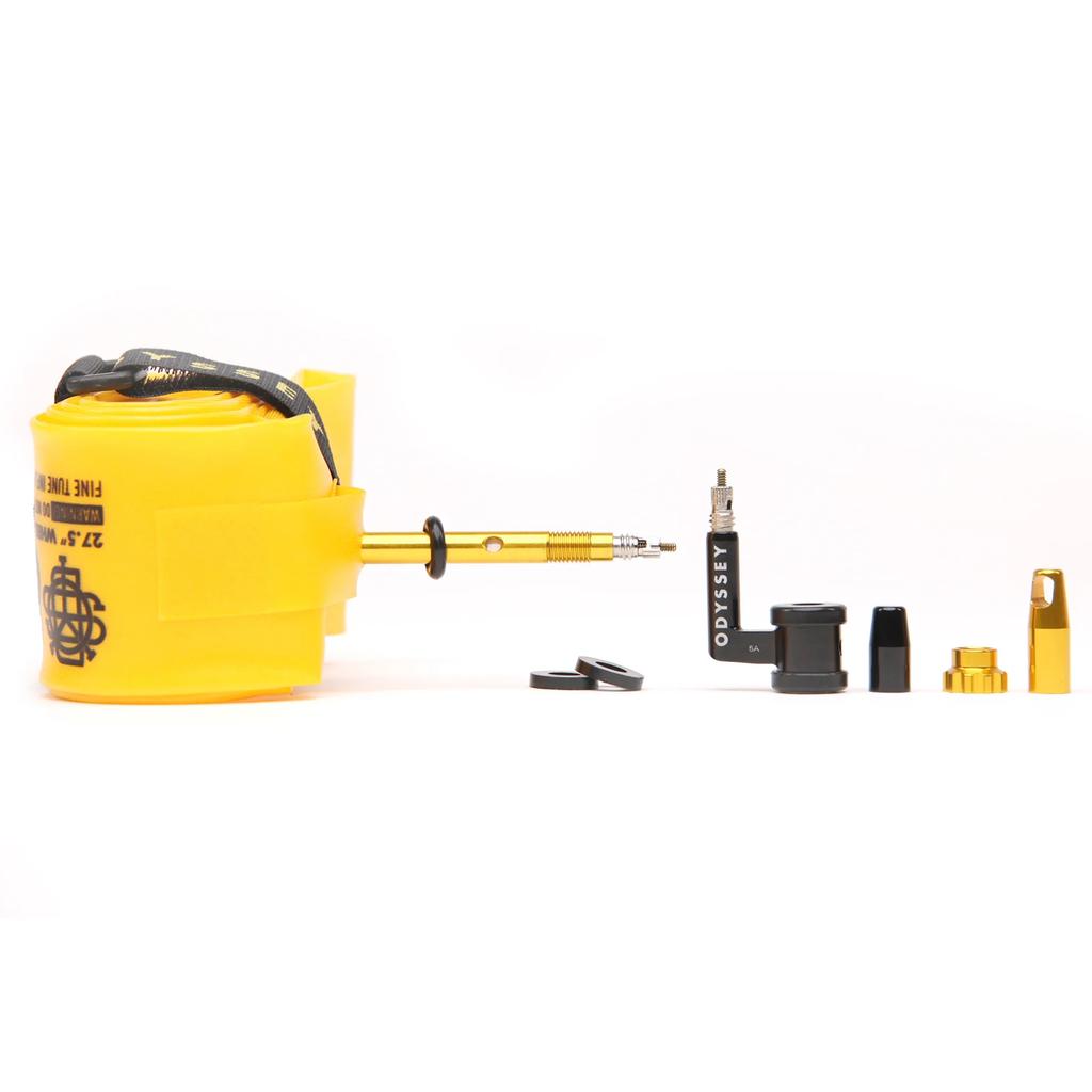 The Odyssey OPTIS Insert With Valve P/V Tube (29 Inch) is shown rolled up in yellow beside black and gold valve components on a white background—designed to boost bike tire performance and improve rim protection.