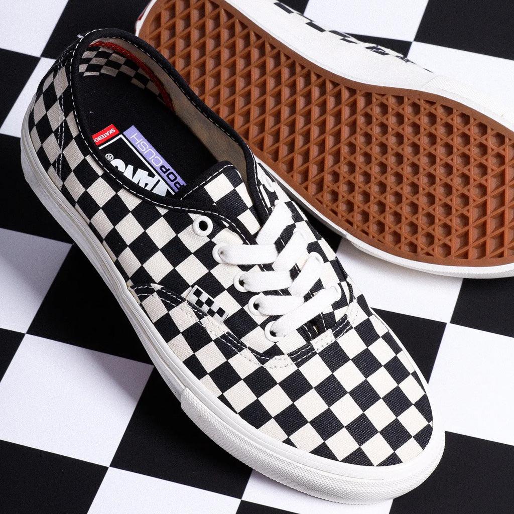 A pair of black and white checkered Vans Pro Skate Authentic Checkerboard Shoes with DURACAP reinforced underlays, providing both comfort and durability, on a checkered checkerboard.