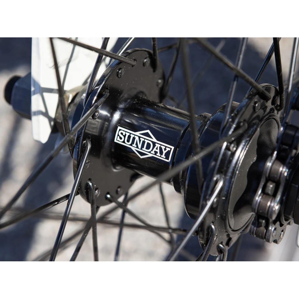 Close-up of the black hub on the Sunday Blueprint 20 Inch Bike (2023), featuring the "Sunday" logo, spokes, and frame. Pro-level geometry fits beginners or advanced riders and allows for Odyssey Springfield brakes.