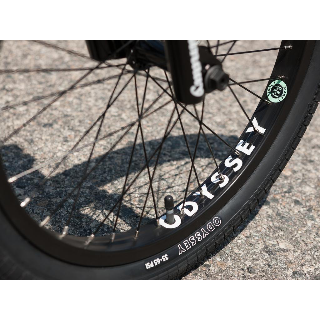 Close-up of a black Sunday Forecaster 20 Inch Bike wheel with "ODYSSEY" rim branding on asphalt, highlighting the quality components.