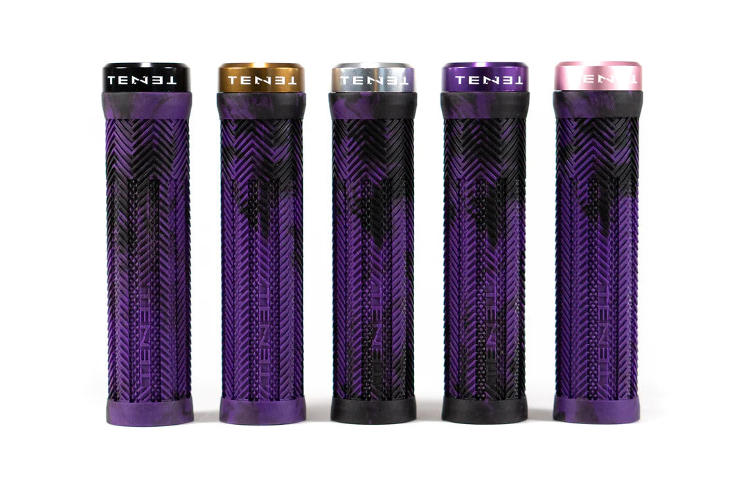 Five cylindrical Tenet Components - Icon Grip mountain bike grips, each adorned with a purple and black pattern, stand upright in a row. Each grip has a distinct end cap color—black, gold, silver, gray, and pink—each labeled "TENET." These lock-on grips are designed with extra-soft rubber for superior comfort and control.