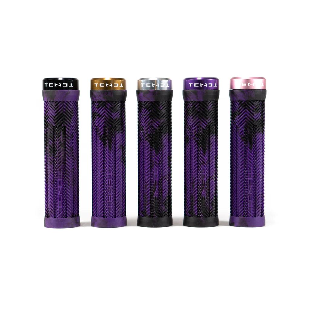 Five cylindrical Tenet Components - Icon Grip mountain bike grips, each adorned with a purple and black pattern, stand upright in a row. Each grip has a distinct end cap color—black, gold, silver, gray, and pink—each labeled "TENET." These lock-on grips are designed with extra-soft rubber for superior comfort and control.