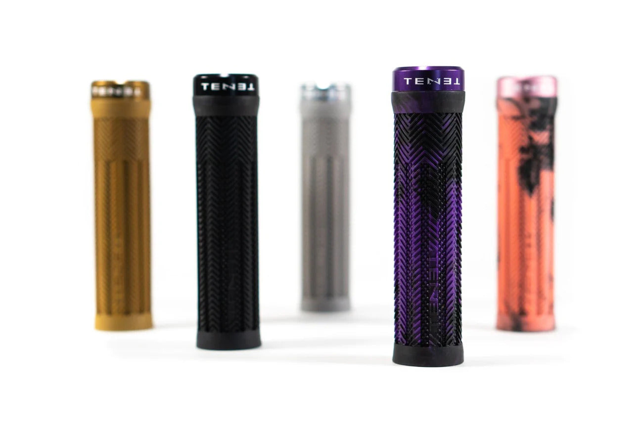Five Tenet Components Icon Grip mountain bike grips in gold, black, gray, purple, and pink—each featuring extra soft textured rubber—stand upright on a white background.