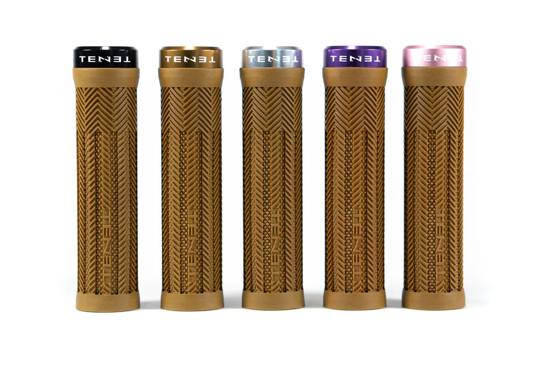 Five Tenet Components Icon Grips in tan with a textured finish and extra soft rubber stand upright in a row on a white background. Each mountain bike grip features a differently colored lock-on end cap—black, gold, silver, purple, and pink—for added style and ensures a secure fit while delivering superior comfort on every ride.