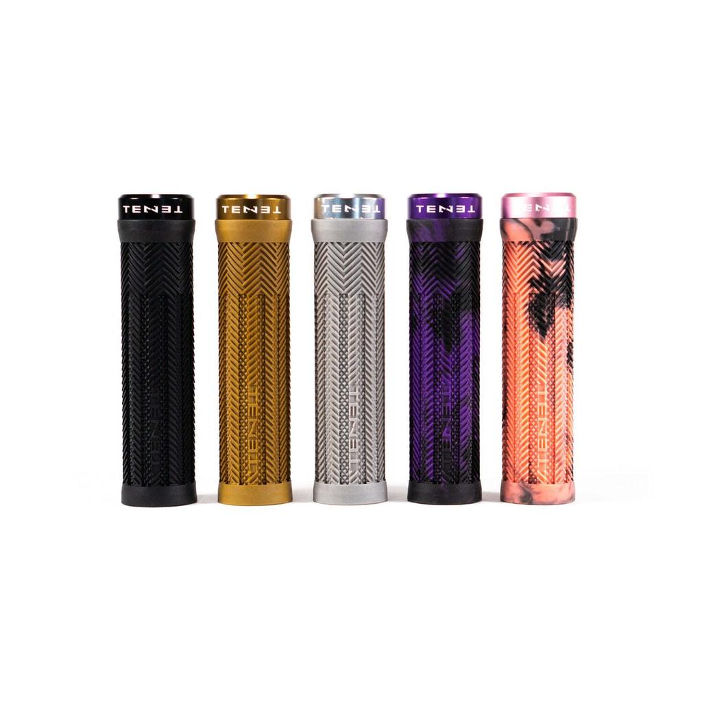 Five Tenet Components Icon Grip textured cylindrical mountain bike grips, in black, gold, silver, purple, and pink camouflage, stand upright side by side on a white background. These extra soft rubber grips are designed for superior comfort and control.