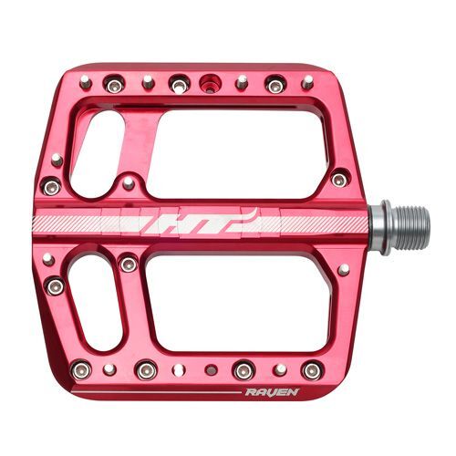 The HT Components ANS12 Raven Pedals feature a red aluminum body, large platform, multiple grip pins, and an axle for easy attachment. "RAVEN" is printed near the edge for a distinct look.
