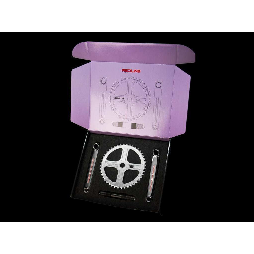 The Redline Vintage Flight 401 Pinchless Crank Set comes in a purple Redline box with foam cutouts, including the crank arms, axle, and chainring—ideal for BMX racers.