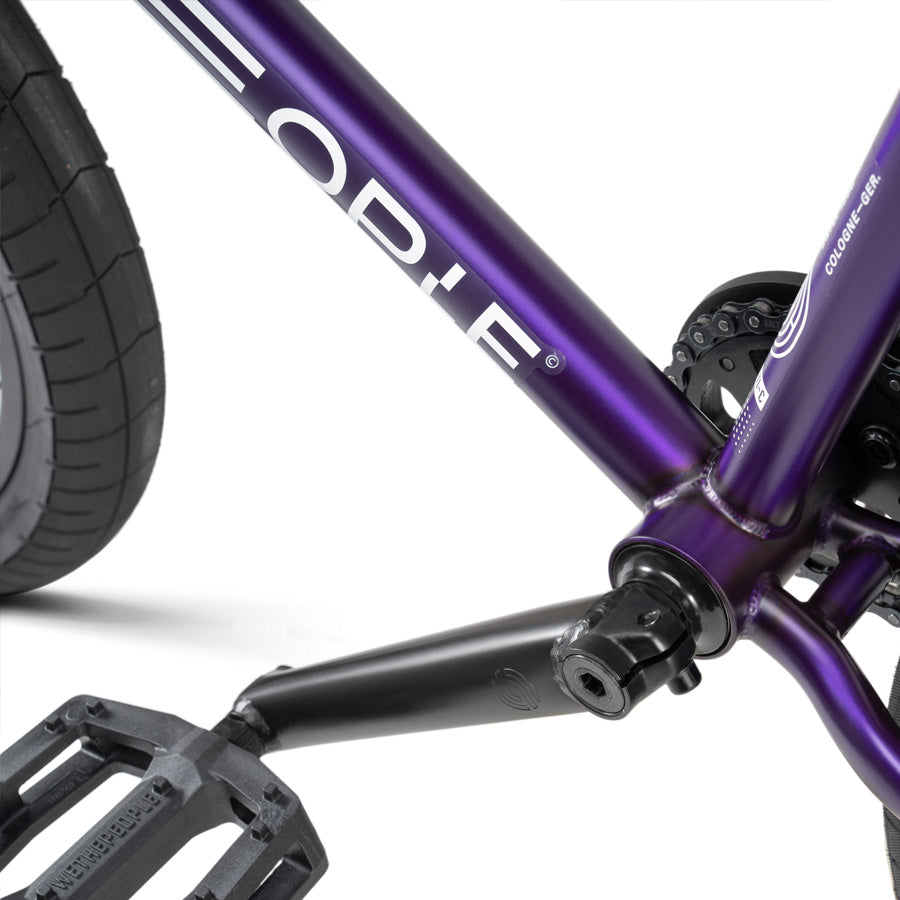 The Wethepeople Reason 20 Inch BMX Bike, a 20 Inch BMX bike designed for urban warriors, features a sleek purple frame with striking black handlebars and pedals.