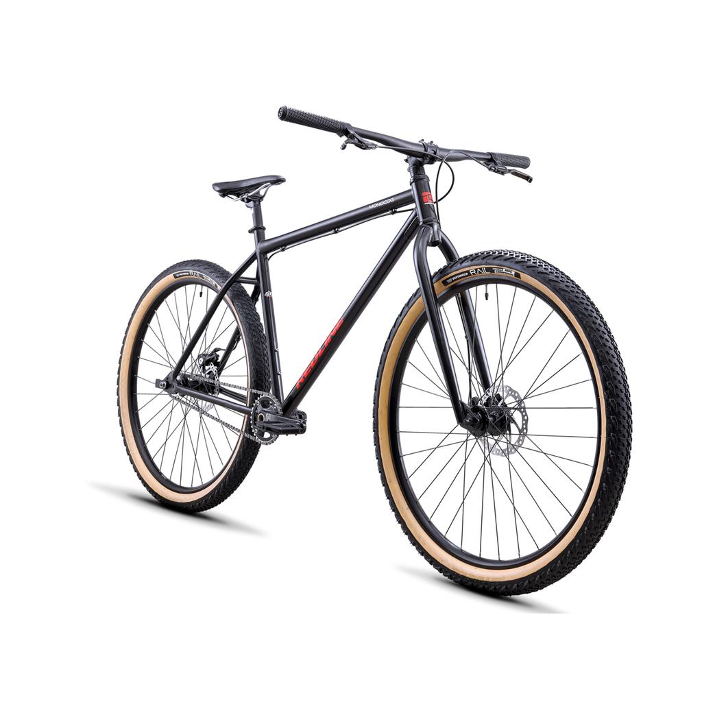 A Redline Monocog 29 Inch Bike in black, featuring singlespeed design, steel frame, flat handlebars, tan-tread tires, and disc brakes, shown against a white background.