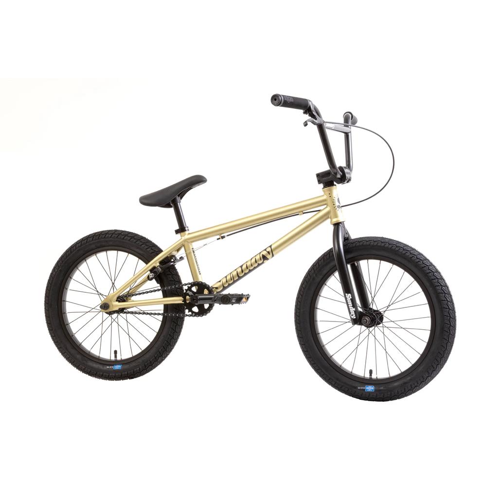 The Sunday Primer 18 Inch Bike (2025) is a gold BMX with black handlebars, seat, pedals, and wheels. It features pro-style frame geometry and is shown on a white background.