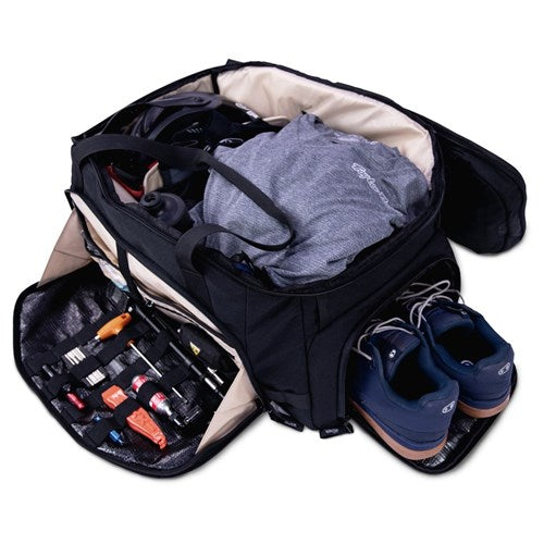 An open Albek Skytrail 51 Gear Bag holding folded clothes, a water bottle, toiletries, personal care items, and blue athletic shoes—ideal for organized gear storage and convenience on the go.