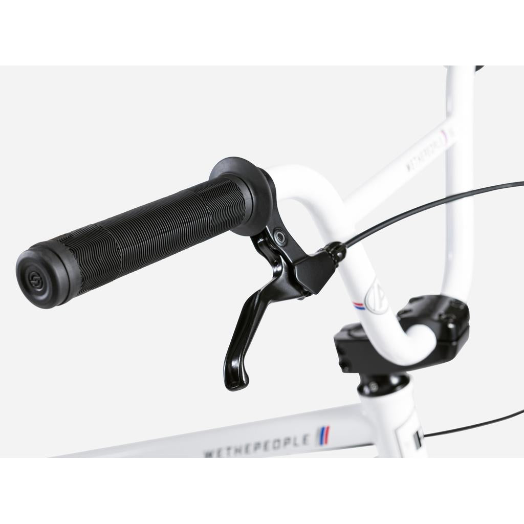 Close-up of a black handlebar grip and brake lever on a Wethepeople Atlas 24 Inch Bike, showing the "WETHEPEOPLE" branding on the white frame.