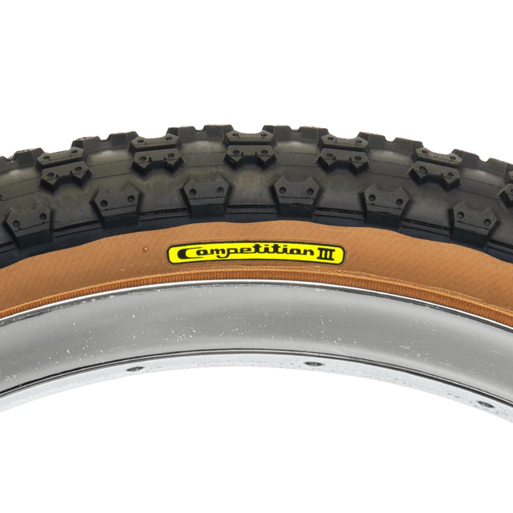 Close-up of a Tioga Comp 3 Skin Wall Tyre (20 Inch) featuring black tread, tan sidewall, and a yellow "Competition III" label mounted on a silver rim.