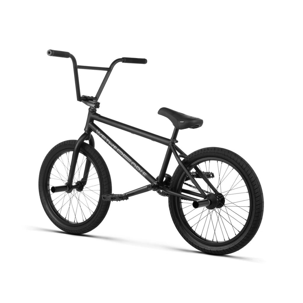 The Wethepeople Reason Shift 20 Inch Bike is a matte black premium BMX with thick tires, high handlebars, a padded saddle, and a full chromoly frame, shown from a slight rear angle against a white background.