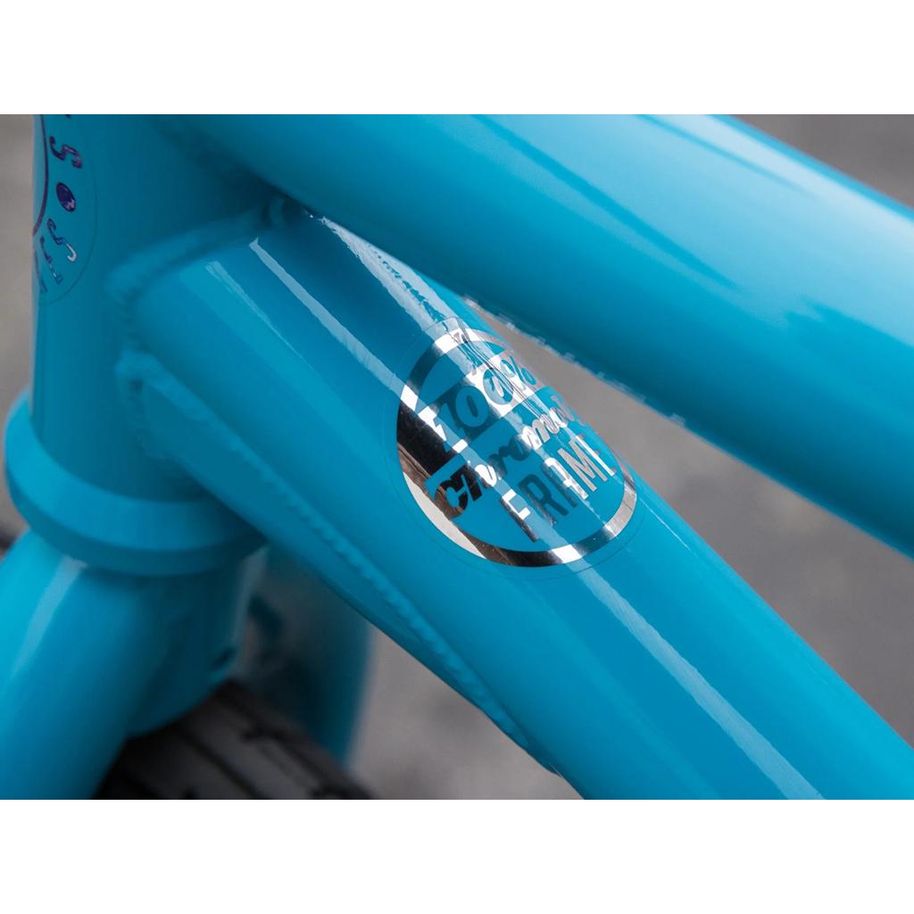 Close-up of the Sunday Forecaster 20 Inch Bike (2025) Aaron Ross edition blue chromoly BMX frame with a metallic badge, visible weld lines, and Odyssey components.