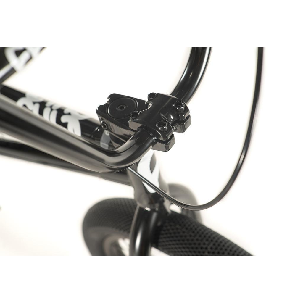 Close-up of the Cult Access 20 Inch Bike’s black handlebar and stem, showing the brake cable and part of the front tire—an ideal choice for those wanting a stylish, durable beginner BMX bike.