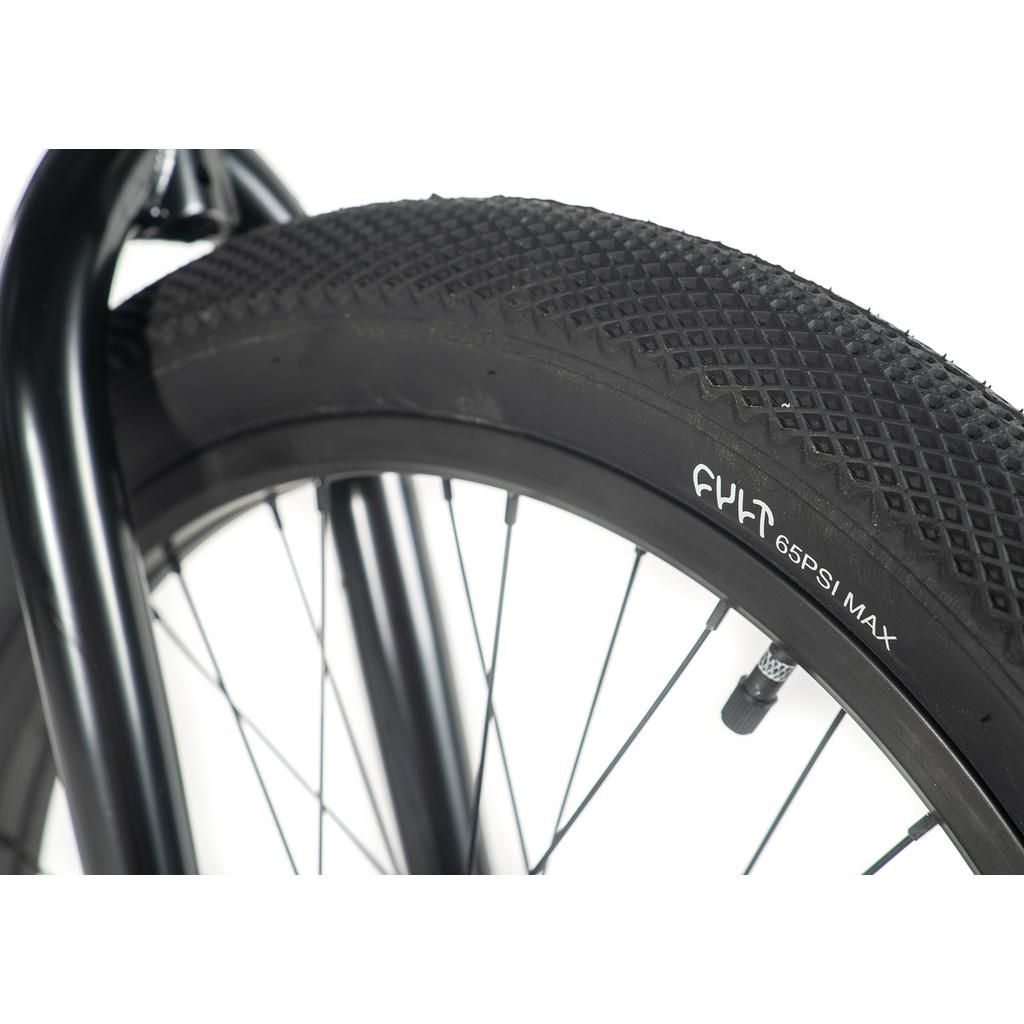 Close-up of the Cult Access 20 Inch Bike's black BMX tire mounted on the wheel, highlighting the valve stem and "65 PSI MAX" text on the sidewall.