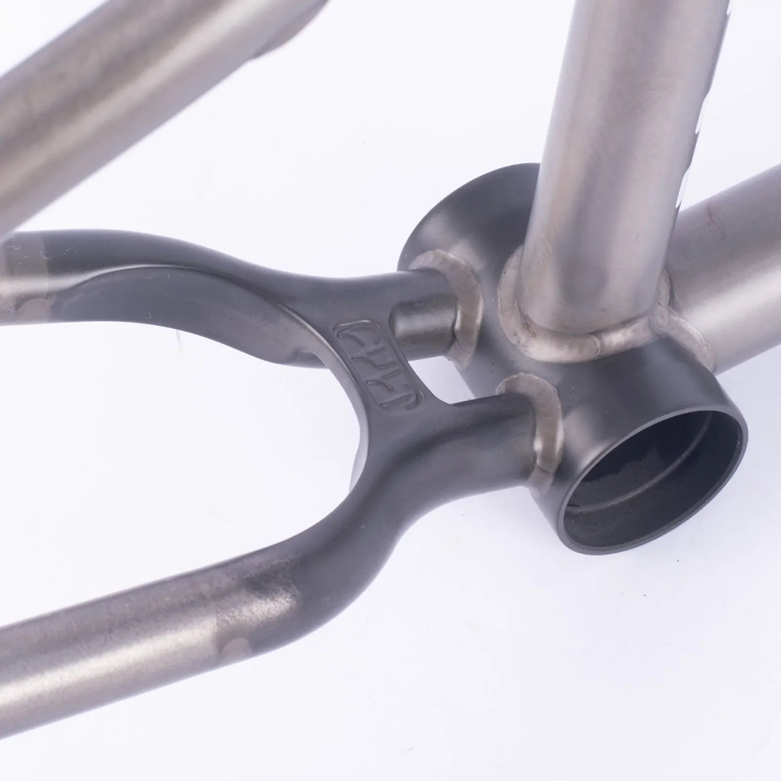 Close-up of a titanium BMX frame’s bottom bracket, highlighting welds and the chainstay, seat tube, and down tube junction—showcasing craftsmanship seen on the Cult Shorty Killian Roth V2 Frame.