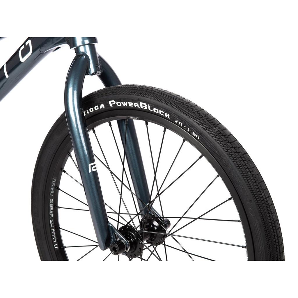 Close-up of a Radio Xenon Expert XL Disc 20 Inch Bike’s front wheel featuring a Tioga PowerBlock tire, black spokes, and a blue fork with pro-level Race BMX components, photographed against a white background.