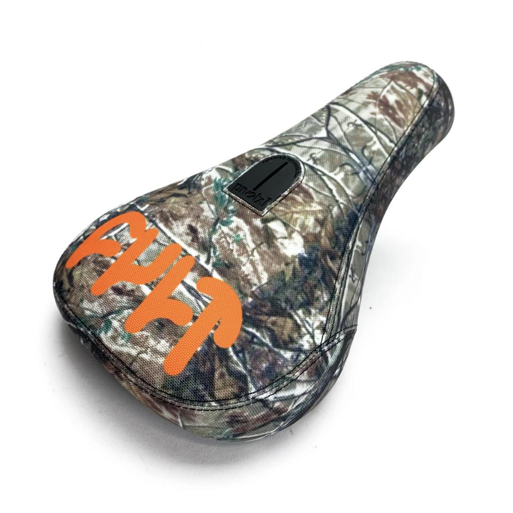 The Cult Tree Camo Fat Pivotal Seat features a camouflage pattern, orange graffiti-style lettering, and a black top label, crafted from durable materials.