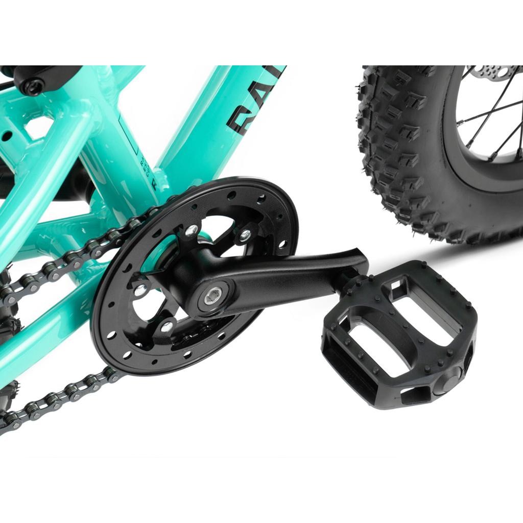 Close-up of the Radio Zuma 14 Inch Bike's pedal, crank arm, chainring, and chain next to its thick tread rear tire—highlighting this lightweight kids’ mountain bike.