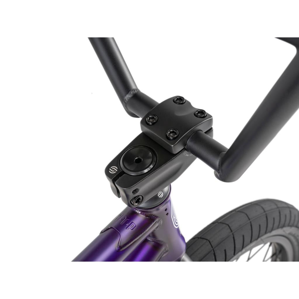 Close-up of the Wethepeople Reason Shift 20 Inch Bike’s premium BMX handlebar and stem, mounted on a full chromoly purple frame with the front tire visible.