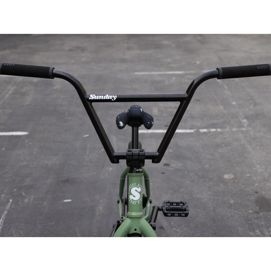Close-up of a pro-level BMX bike’s handlebars, seat, and pedals on pavement, featuring “Sunday” branding and the 2025 Sunday Forecaster 20 Inch Bike (Brett Silva) with its 100% chromoly frame.