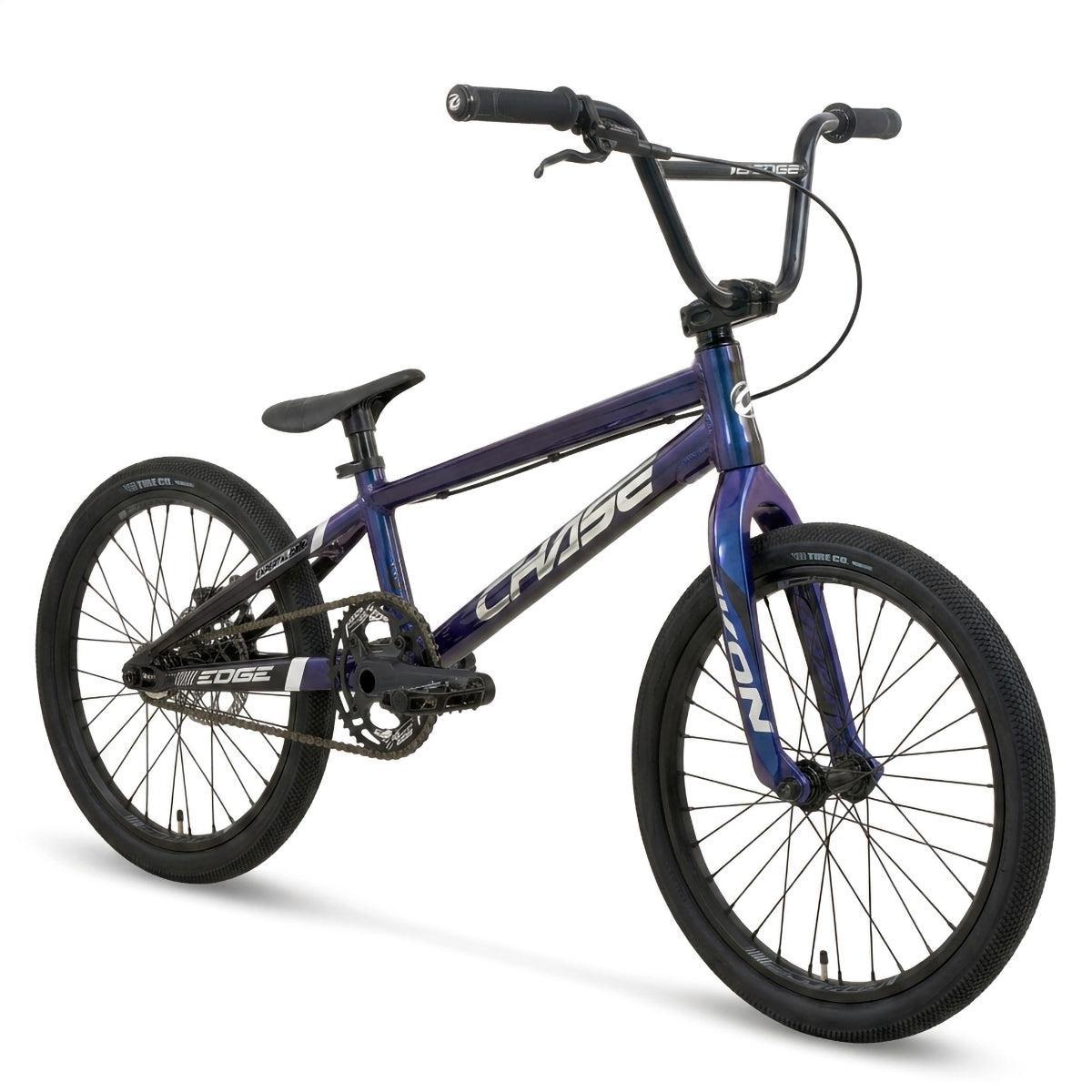 A blue Chase Edge Expert XL CF Race Bike (2027) with black tires, a straight handlebar, and a compact frame featuring a sleek carbon fork. The bike is positioned at an angle facing left.