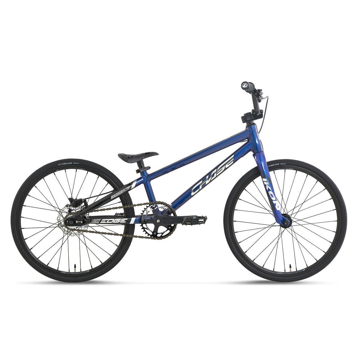 The Chase Edge Junior CF Race Bike (2027), a blue BMX bicycle featuring a lightweight frame, flat handlebars, carbon fork, black tires, and a single gear, is displayed in side profile against a white background.