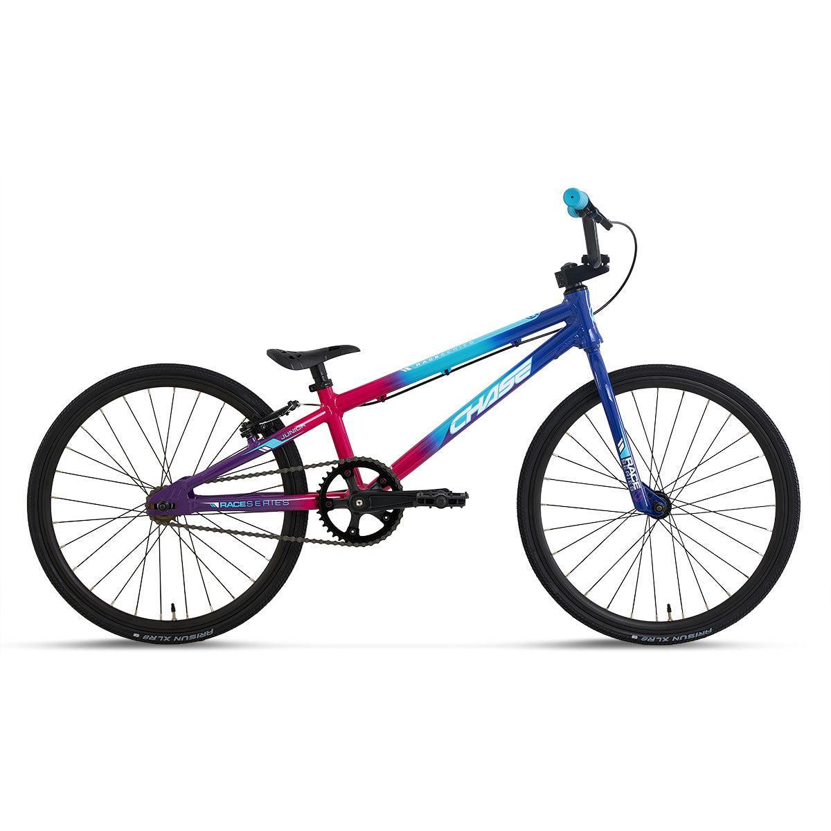 The Chase Race Series Junior Race Bike (2027) features a gradient frame in blue, pink, and purple, with black tires, saddle, and handlebars; it is shown from the side against a white background.