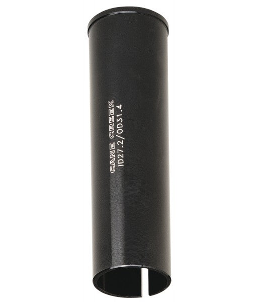 Black cylindrical Cane Creek 26.6 to 25.4 Seat Post Shim with a vertical slit at the bottom and white branding text on the side.