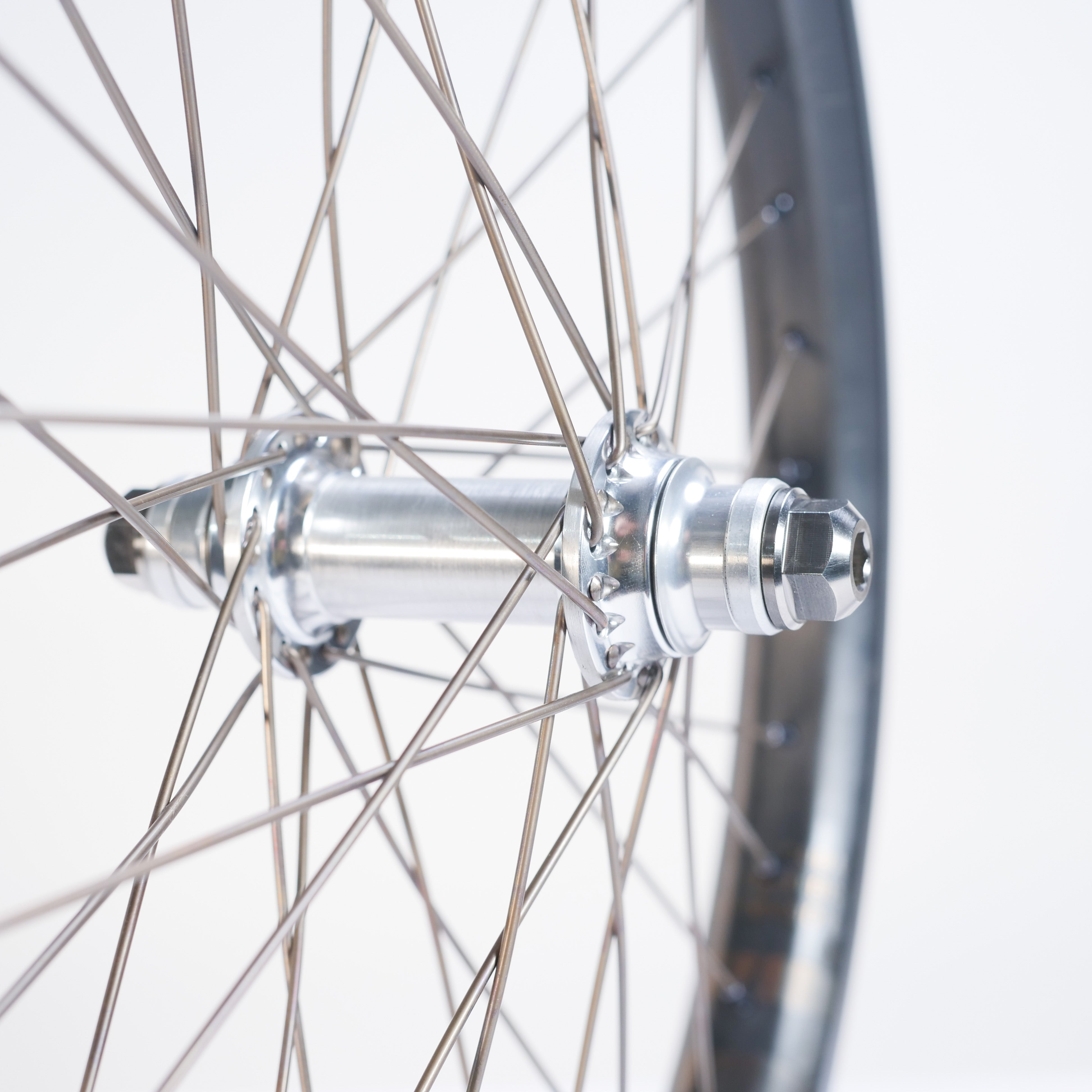 Close-up of the ION BMX C20 Carbon Titanium V1.5 Planetary 20 Inch Wheelset, showing titanium spokes, a silver hub, and part of the black rim against a white background.