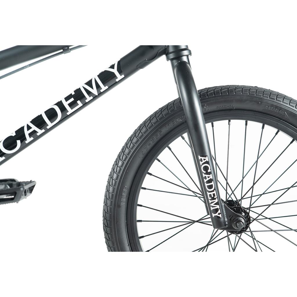 Close-up of the Academy Inspire 18 Inch Bike in black, showing the front tire, fork, and frame with "ACADEMY" in white text. Ideal BMX for kids.