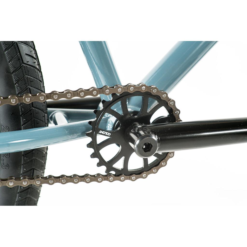 Close-up of the crank, chainring, and chain on the Colony Eclipse 26 Inch Bike’s blue chromoly frame with a black tire, shown against a white background.