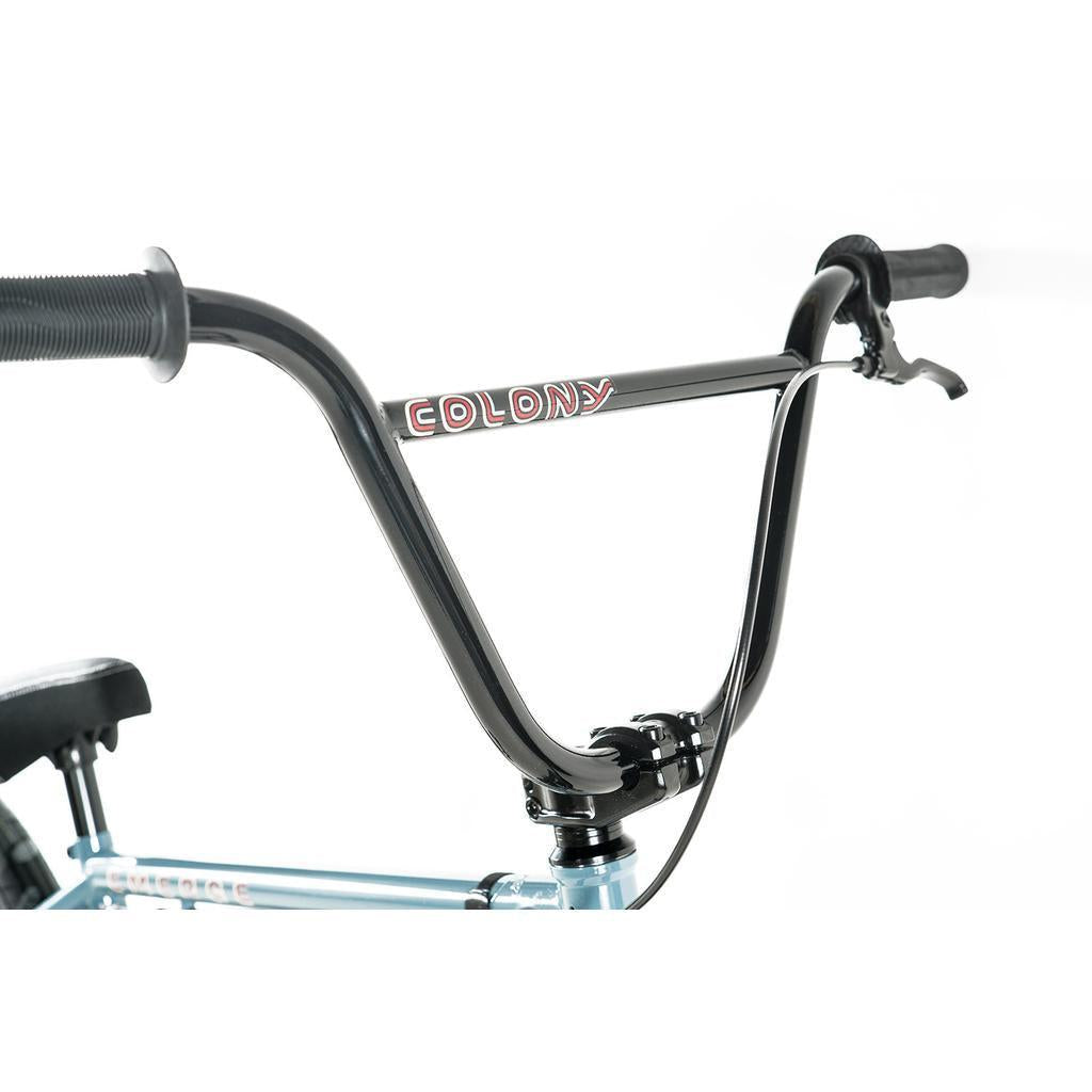 Close-up of black Colony BMX handlebars with brake lever, mounted on a light blue chromoly frame of the Colony Emerge 20 Inch Bike against a white background.