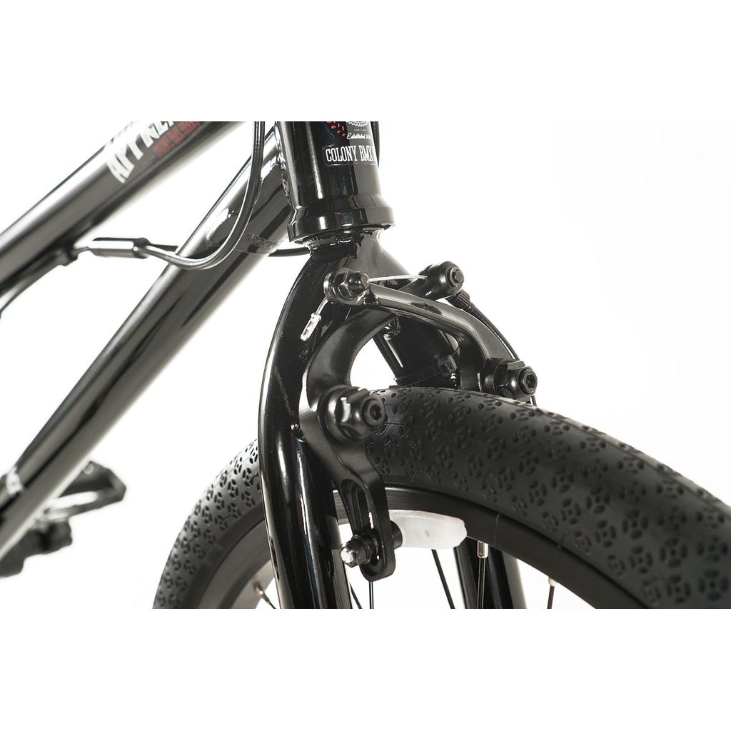 Close-up of the Colony Apprentice Flatland 20 Inch Bike's black front wheel, showing the tire tread, fork, and caliper brake against a white background—a detailed view of this BMX flatland bike.
