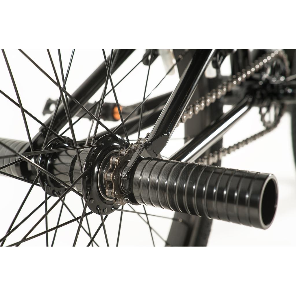 Close-up of a Colony Apprentice Flatland 20 Inch Bike rear wheel, showcasing black spokes, chain, hub, and metal peg on the axle—ideal features for mastering flatland BMX tricks.