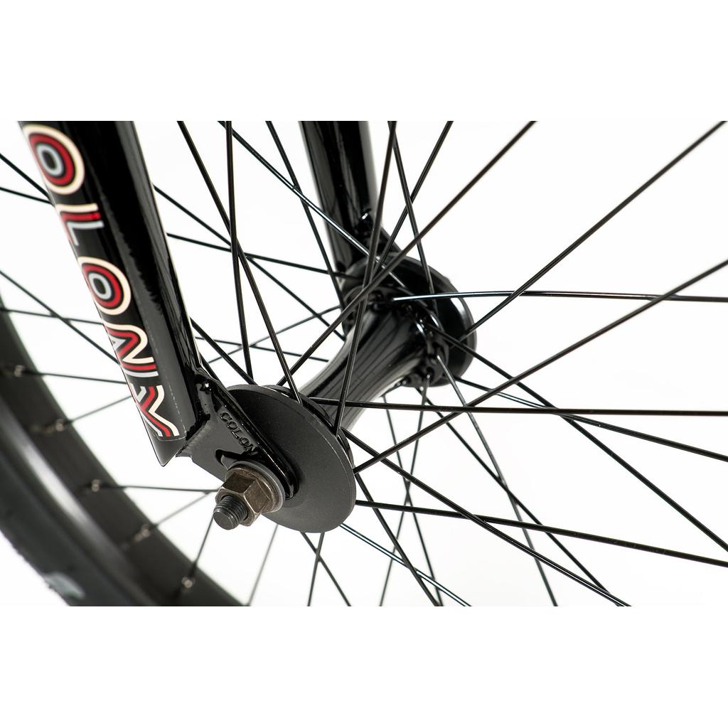 Close-up of a Colony Emerge 20 Inch Bike wheel, highlighting black spokes, a hub, and part of the front fork with "COLONY" branding—an ideal match for Colony Emerge aftermarket parts or a durable Chromoly frame.