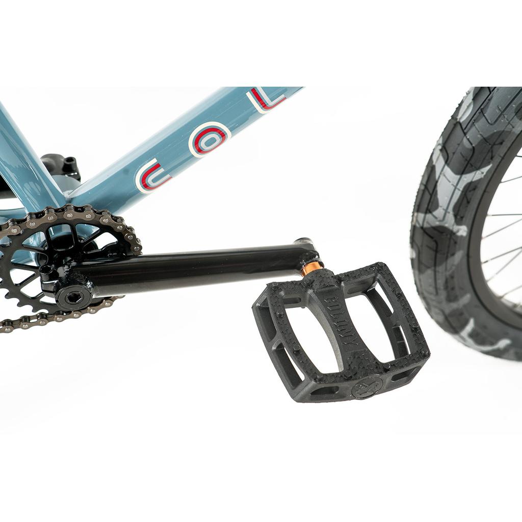 Close-up of a black pedal attached to the crank arm on the Colony Emerge 20 Inch Bike, highlighting its sturdy frame, visible chain, and rear wheel—showcasing quality BMX design.