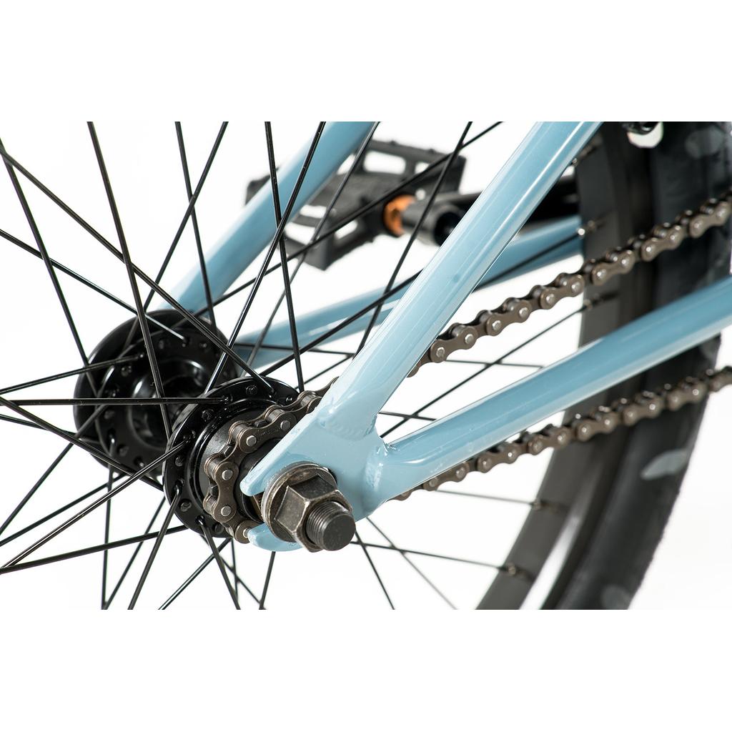 Close-up view of the Colony Emerge 20 Inch Bike's rear wheel, highlighting the chain, sprocket, axle, spokes, and part of its blue BMX chromoly frame.