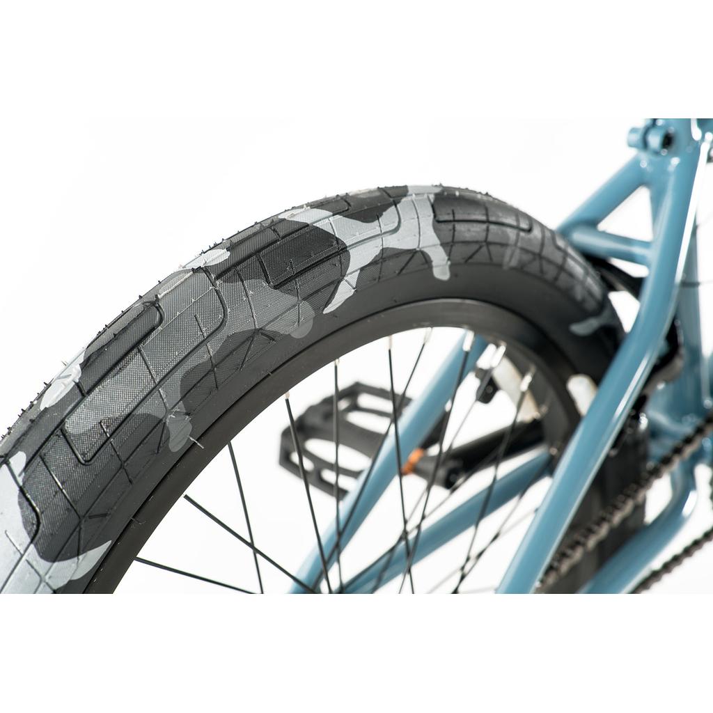 Close-up view of the Colony Emerge 20 Inch Bike’s rear wheel with a black and gray camo-patterned tire, blue Chromoly frame, plus visible pedal and spokes.